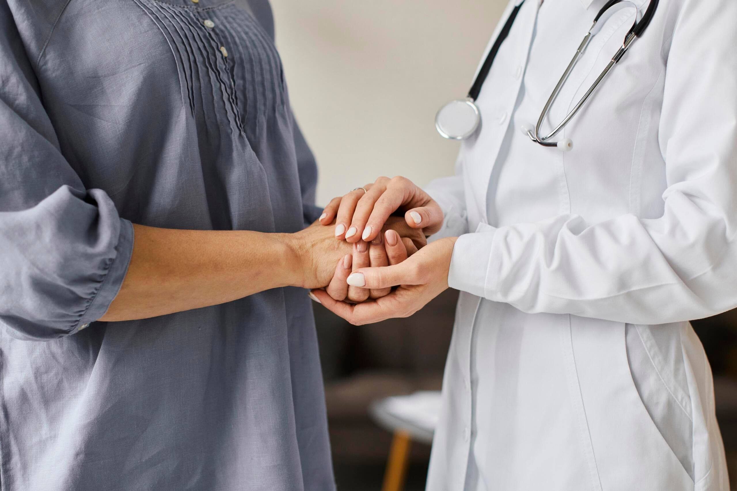 Médica segurando as mãos de uma paciente